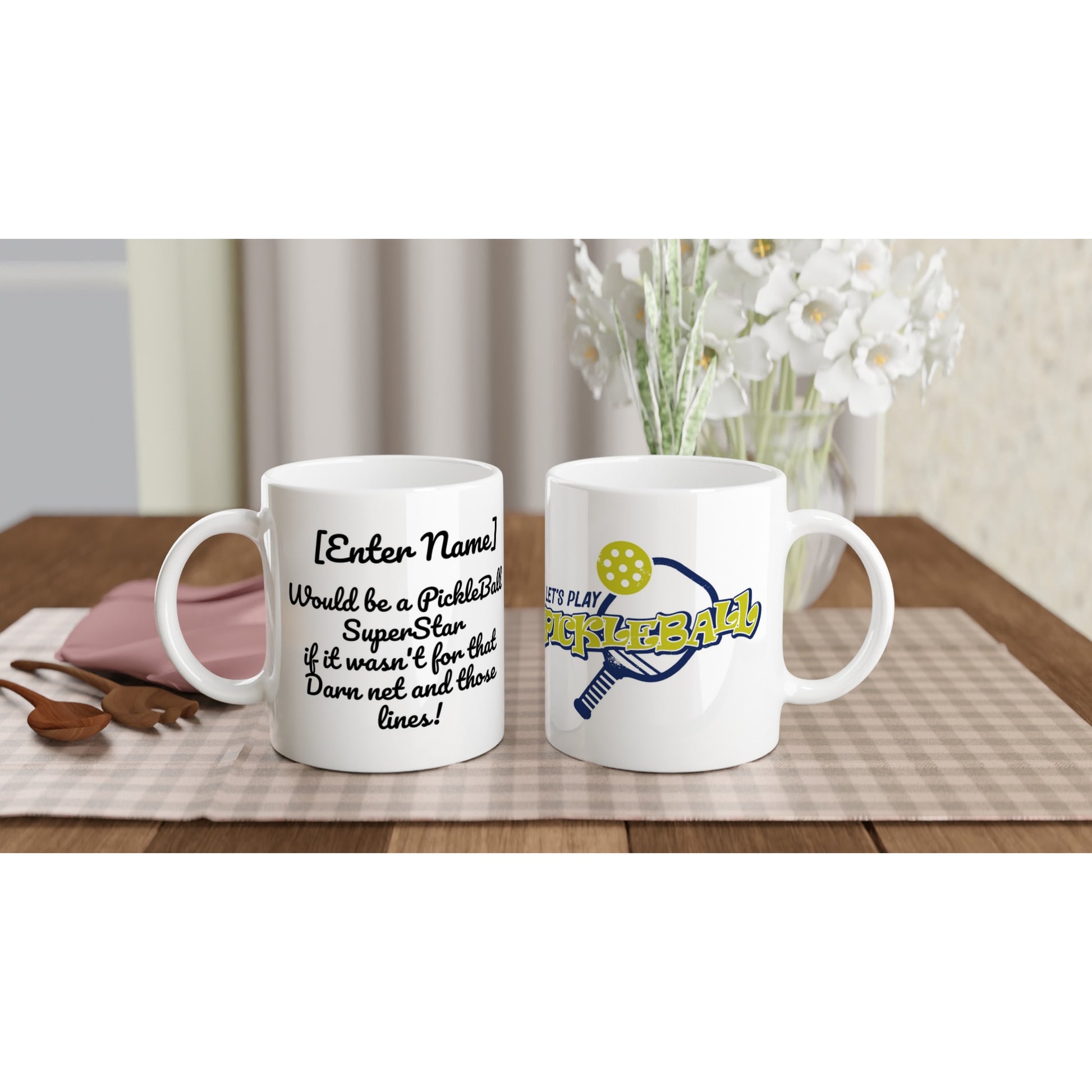 Two Personalized white ceramic 11oz mugs with motto Your Name Would be a PickleBall Superstar if it wasn’t for that Darn net and those lines on front and Let's Play PickleBall logo on back coffee mugs are dishwasher and microwave safe from WhatYa Say Apparel sitting on coffee table with green and white placemat.