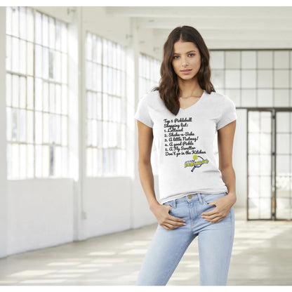 Brown haired Female model wearing original motto Top 5 PickleBall list premium women’s V-neck t-shirt from WhatYa Say Apparel standing with thumbs in front pockets.