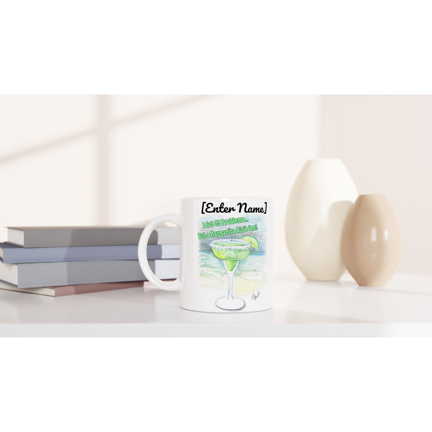Personalized white ceramic 11oz mug with motto I Got 99 Problems But a Margarita Aint One on the front and WhatYa Say logo on the back  dishwasher and microwave safe from WhatYa Say Apparel sitting on coffee table with books and two vases.