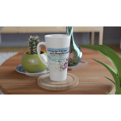 A Seventeener white ceramic 17oz mug with original motto I need my Ass in the Sand and a Margarita in my hand on front and WhatYa Say logo on back dishwasher and microwave safe from WhatYa Say Apparel sitting on coaster on coffee table with green potted cactus and silver vase.