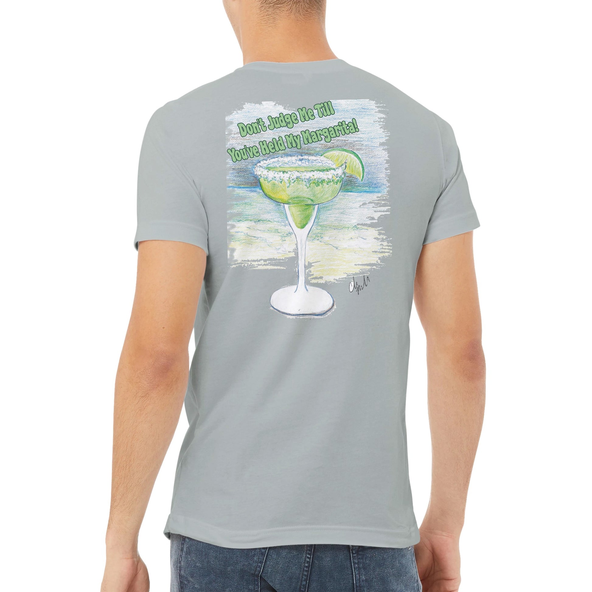 A ash premium unisex v-neck t-shirt with original artwork and motto Dont Judge Me Till You've Held My Margarita on back and WhatYa Say logo on front made with combed and ring-spun cotton from WhatYa Say Apparel worn by A brown-haired male back view.
