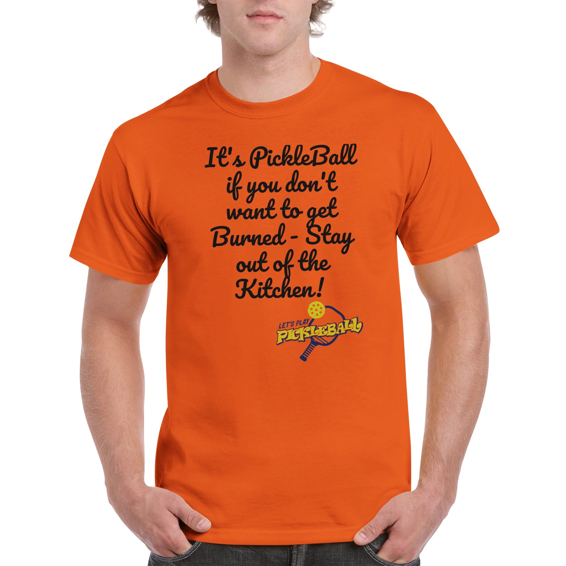 Orange comfortable Unisex Crewneck heavyweight cotton t-shirt with funny saying It’s PickleBall if you don’t want to get Burned – Stay out of the Kitchen! and Let’s Play Pickleball logo on the front from WhatYa Say Apparel worn by blonde-haired male front view.