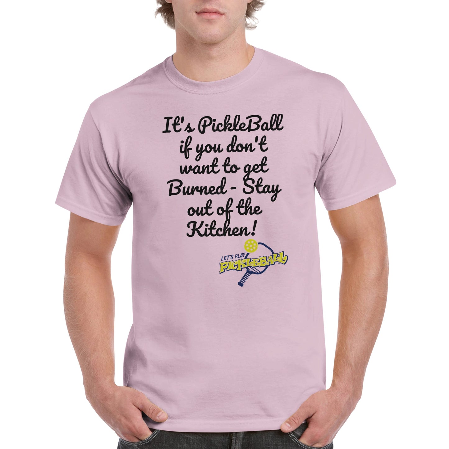 Light Pink comfortable Unisex Crewneck heavyweight cotton t-shirt with funny saying It’s PickleBall if you don’t want to get Burned – Stay out of the Kitchen! and Let’s Play Pickleball logo on the front from WhatYa Say Apparel worn by blonde-haired male front view.