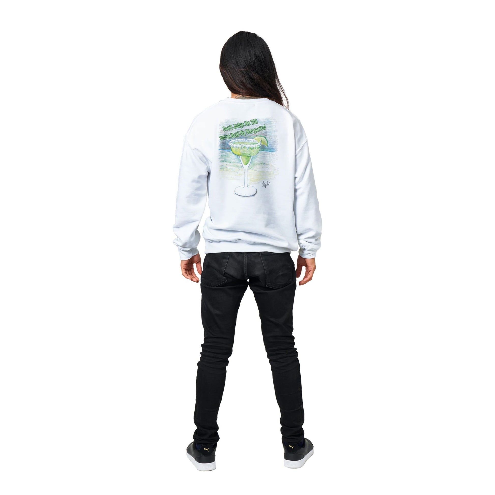Standing long black-haired male model wearing a white Classic Unisex Crewneck sweatshirt with original artwork and motto Don’t Judge Me Till You’ve Held my margarita on back and Whatya Say logo on front from WhatYa Say Apparel rear view.