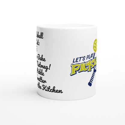 White ceramic 11oz mug with original motto Top 5 Pickleball Shopping list lettuce, Shake-n-bake, Nutmeg, Pickle, a Fly Swatter Don’t go in the kitchen front side and Let's Play PickleBall logo on back coffee mug dishwasher and microwave safe from WhatYa Say Apparel side view.