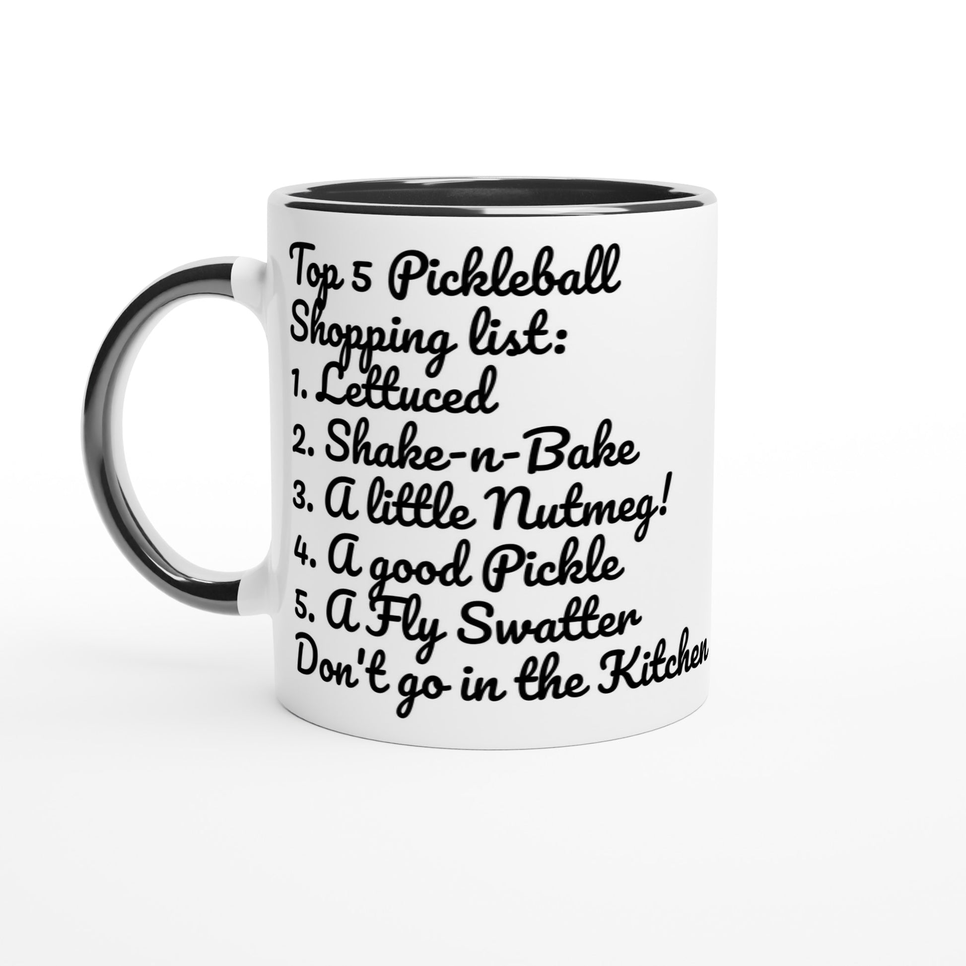 White ceramic 11oz mug with black handle original motto Top 5 Pickleball Shopping list lettuce, Shake-n-bake, Nutmeg, Pickle, a Fly Swatter Don’t go in the kitchen front side and Let's Play PickleBall logo on back dishwasher and microwave safe ceramic coffee mug from WhatYa Say Apparel front view.