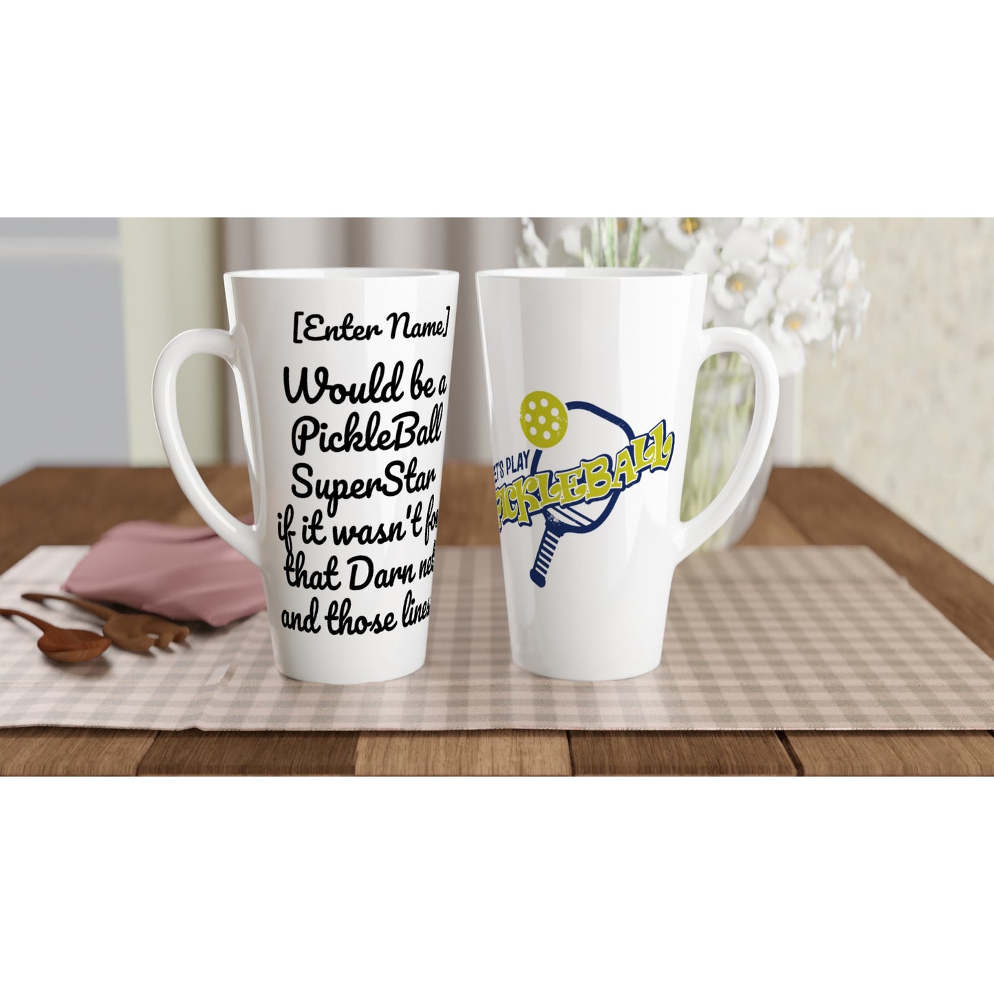 Two Personalized Seventeener white ceramic 17oz mug with original personalized motto [Your Name] Would be a PickleBall SuperStar if it wasn’t for that Darn net and those lines! on front and Let’s Play Pickleball logo on back coffee mug dishwasher and microwave safe from WhatYa Say Apparel sitting on coffee table with green and white placemat.