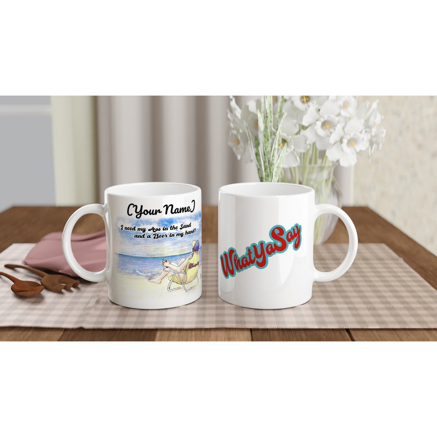 Two White personalized ceramic 11oz mugs with personalized motto [Enter Name] I need my Ass in the Sand and a Beer in my hand on front and WhatYa Say logo on back coffee mugs are dishwasher and microwave safe from WhatYa Say Apparel sitting on coffee table with green and white placemat.