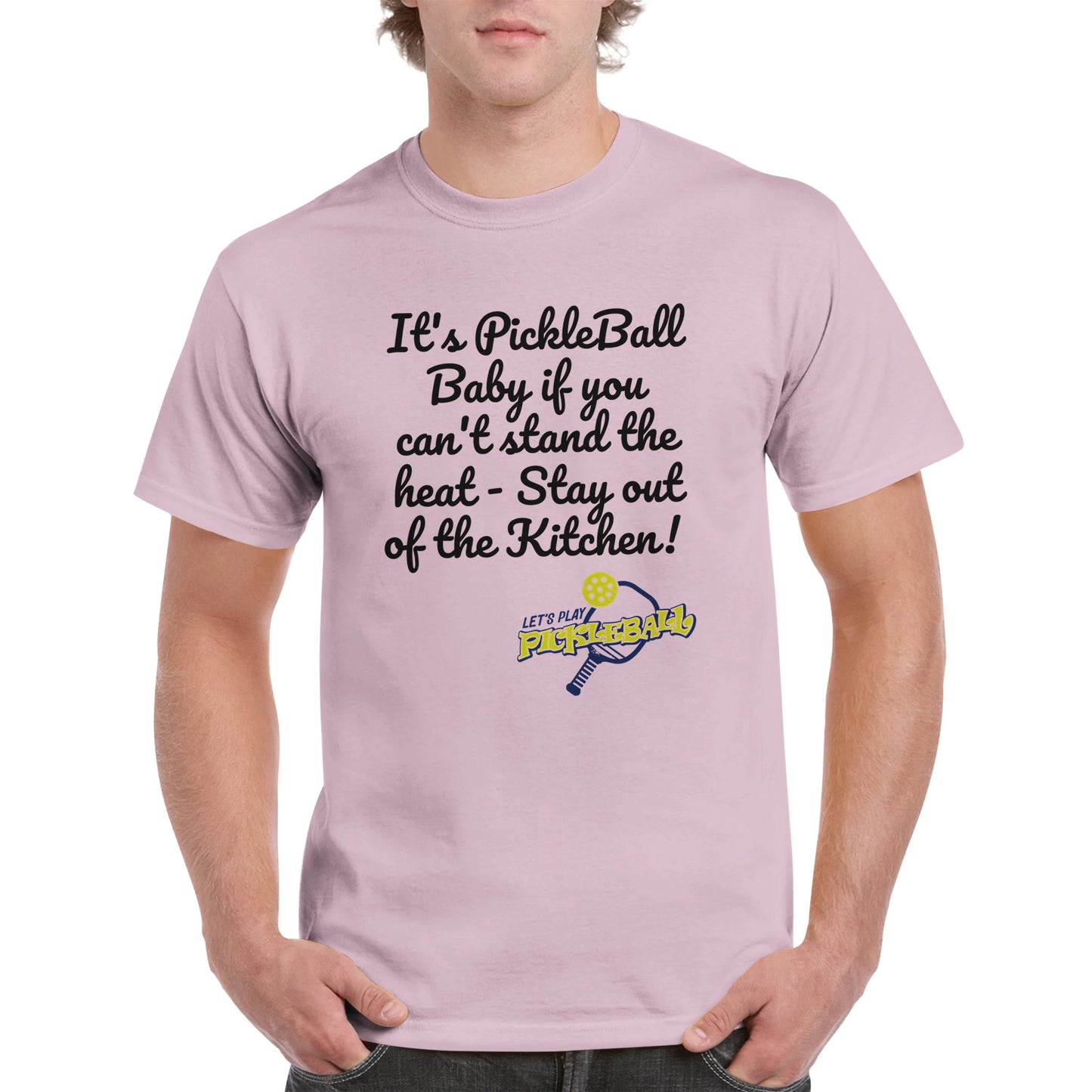 Light pink comfortable Unisex Crewneck heavyweight cotton t-shirt with funny saying It’s PickleBall Baby if can’t stand the heat – Stay out of the Kitchen!  and Let’s Play Pickleball logo on the front from WhatYa Say Apparel worn by blonde-haired male front view.