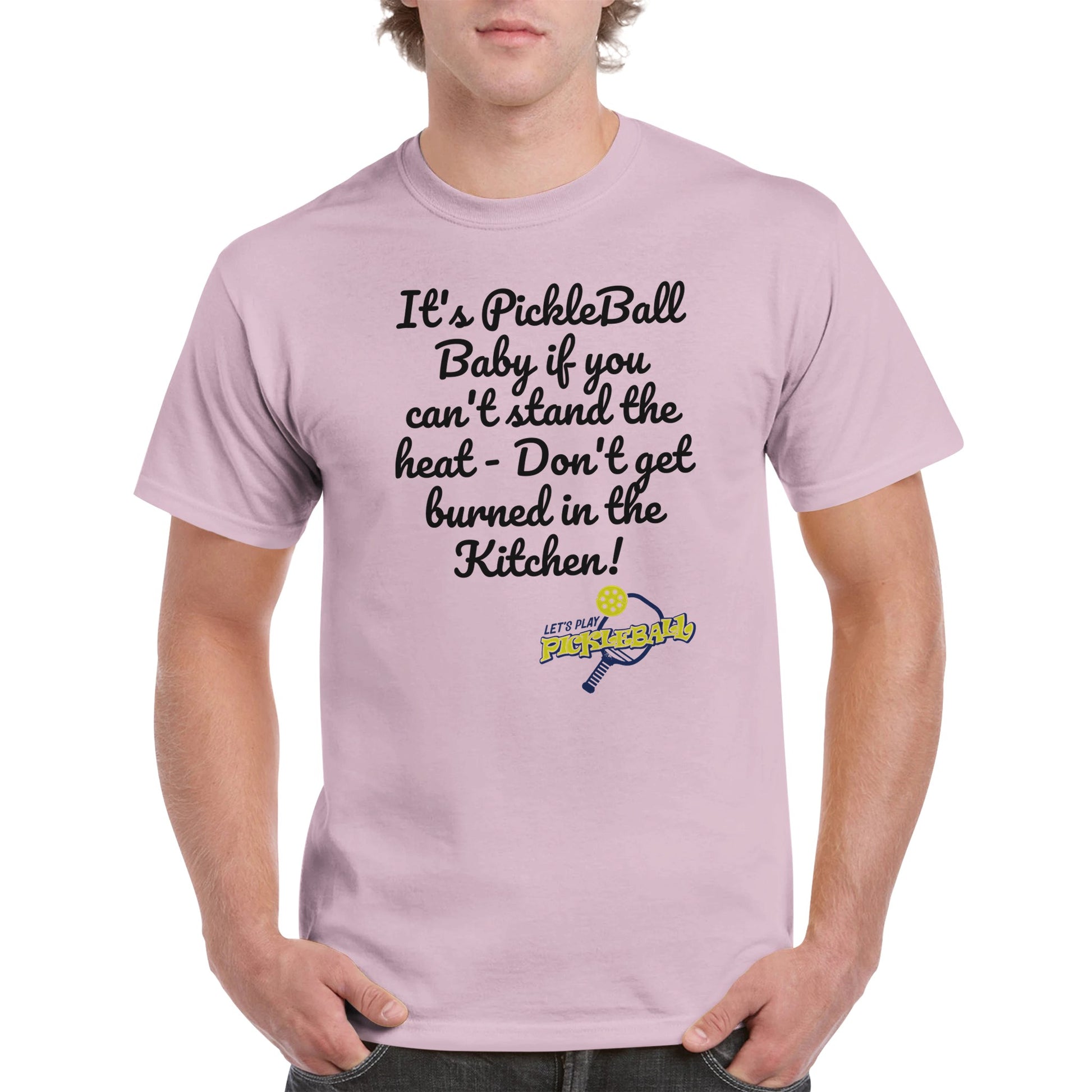 Light pink comfortable Unisex Crewneck heavyweight cotton t-shirt with funny saying It’s PickleBall Baby if can’t stand the heat – Don’t get burned in the Kitchen!  and Let’s Play Pickleball logo on the front from WhatYa Say Apparel worn by blonde-haired male front view.
