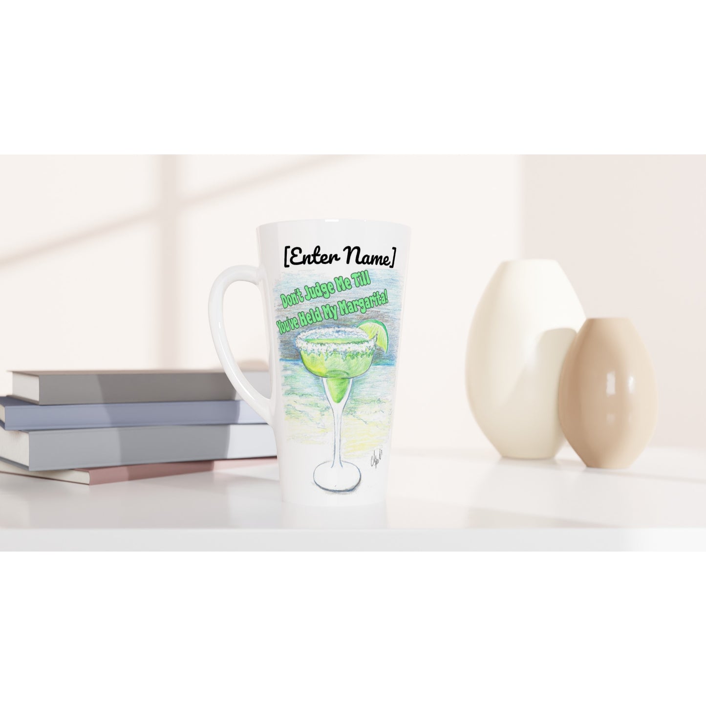 Personalized Seventeener white ceramic 17oz mug with motto Don't Judge Me till You've Held my Margarita dishwasher and microwave safe from WhatYa Say Apparel sitting on coffee table with books and two vases.