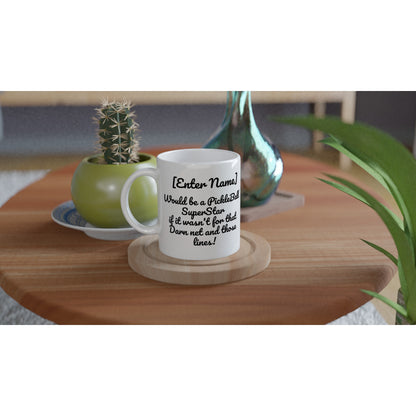 Personalized White ceramic 11oz mug Personalized with motto Your Name Would be a PickleBall Superstar if it wasn’t for that Darn net and those lines and Let's Play Pickleball logo on back coffee mug dishwasher and microwave safe from WhatYa Say Apparel sitting on coaster on coffee table with green potted cactus and silver vase.